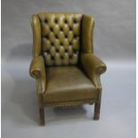 An olive green buttoned leather winged armchair Please Note: This furniture was either not