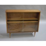 Teak bookcase with two glass sliding doors to the canted front on tapered rounded legs with button