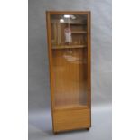 A teak and glazed cabinet by Pedley of Saffron Walden, fitted interior, over a drop front base,