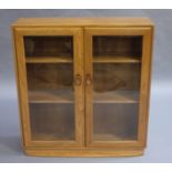 An Ercol elm and glazed two door bookcase with curved plinth base,