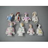 Eight half length porcelain dolls heads, variously dressed some with hats,