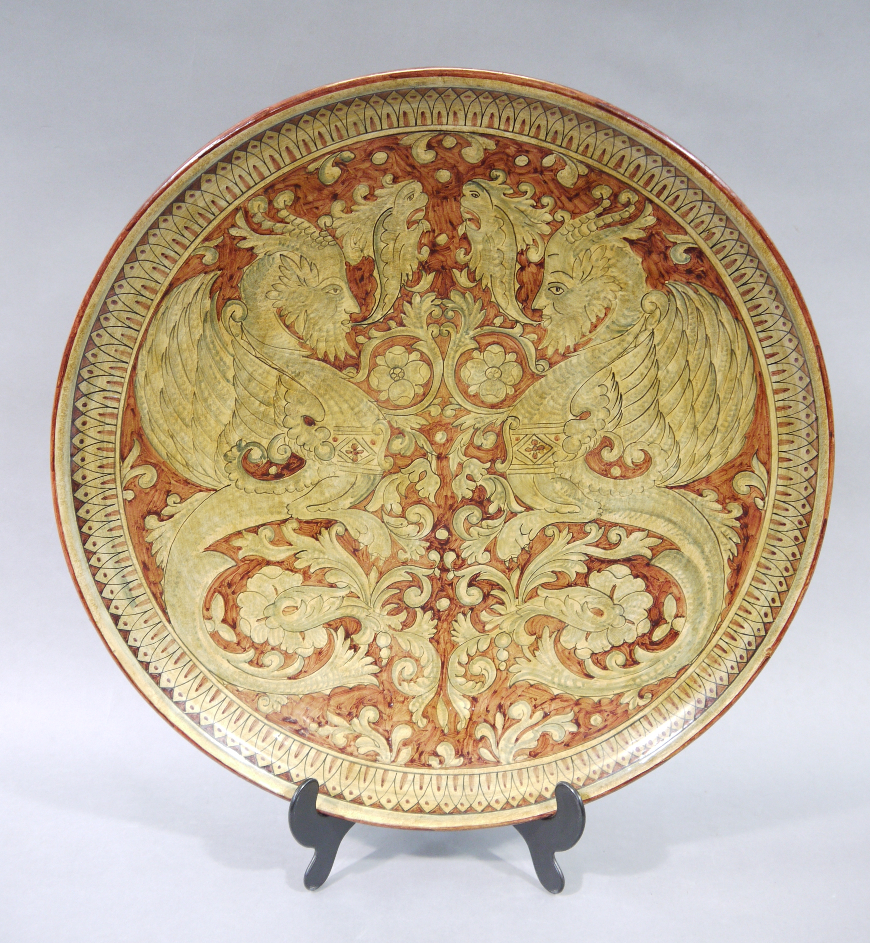 A large Italian pottery circular charger painted with a pair of mythical beast and stylised sea