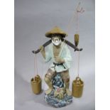 A pottery figure of a Japanese fisherman with hanging baskets and carp,