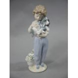 A Lladro figure of a young boy holding a puppy,