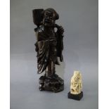 A Chinese hardwood figure of a boy carrying a leafy branch, 33cm high; a resin figure of a deity,