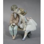 A Lladro Anniversary Edition figure of a young boy and girl seated on a bench,