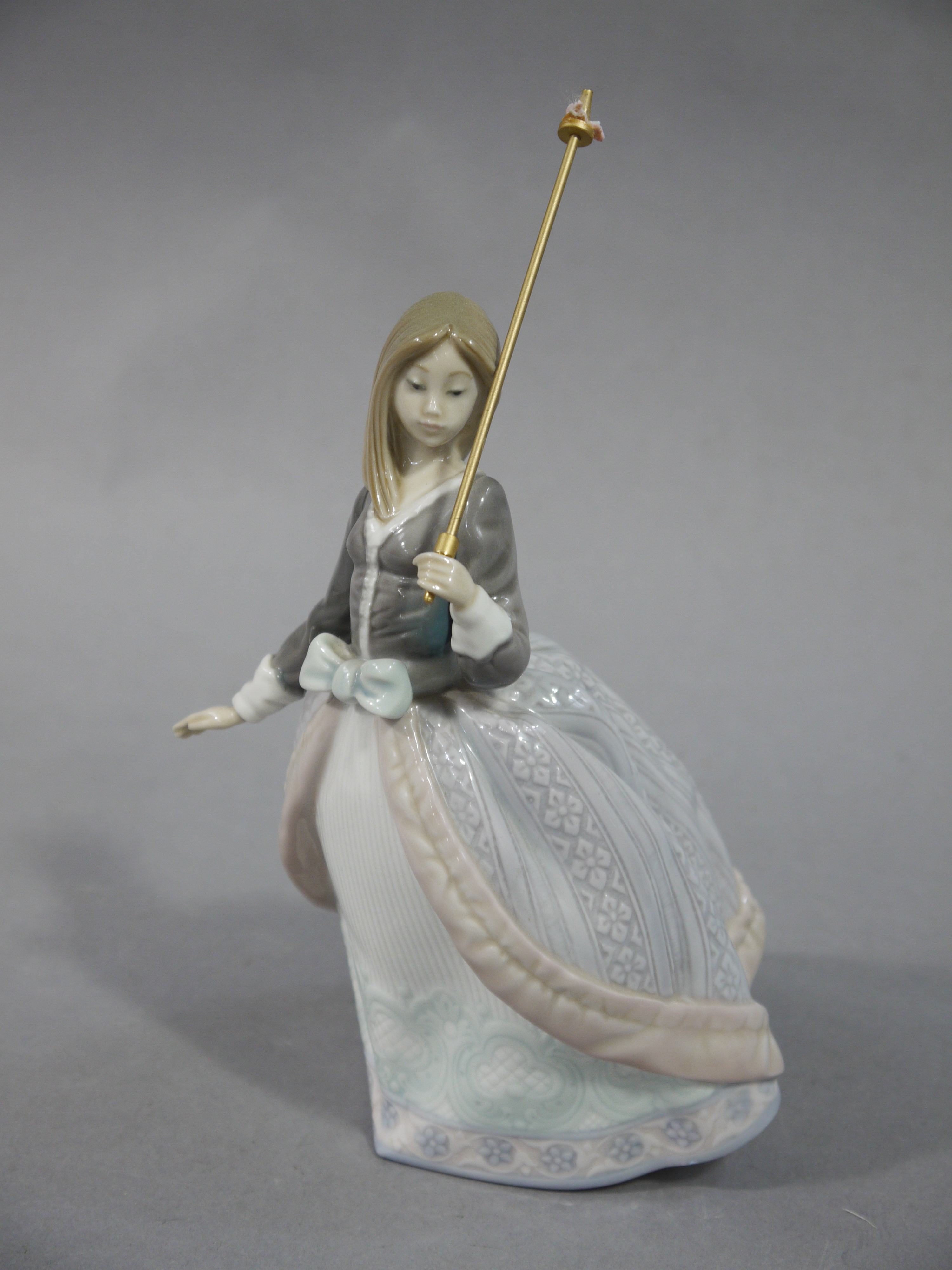 A Lladro figure of a young woman with a parasol,