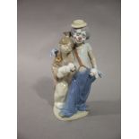 A Lladro figure of a clown and child each carrying a puppy,