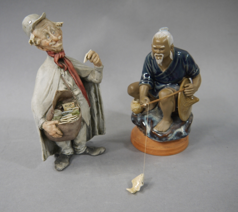 An Italian bisque porcelain figure of a postman, 18cm; a porcelain figure of a Chinese fisherman,