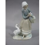 A Lladro figure of a woman carrying geese and a basket with goose at her feet,