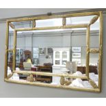 A reproduction gilt framed mirror, reeded with floral clasps,