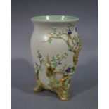 A Clarice Cliff urnular vase moulded in relief with prunus trees, on three trunk feet, 19cm high,