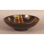 A slip decorated circular pedestal bowl, the dark "toffee" interior with four tree panels,