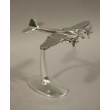 A reproduction white metal model of an aeroplane on stand,