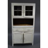 A vintage kitchen cabinet having two cupboard doors above an open compartment with pull out enamel