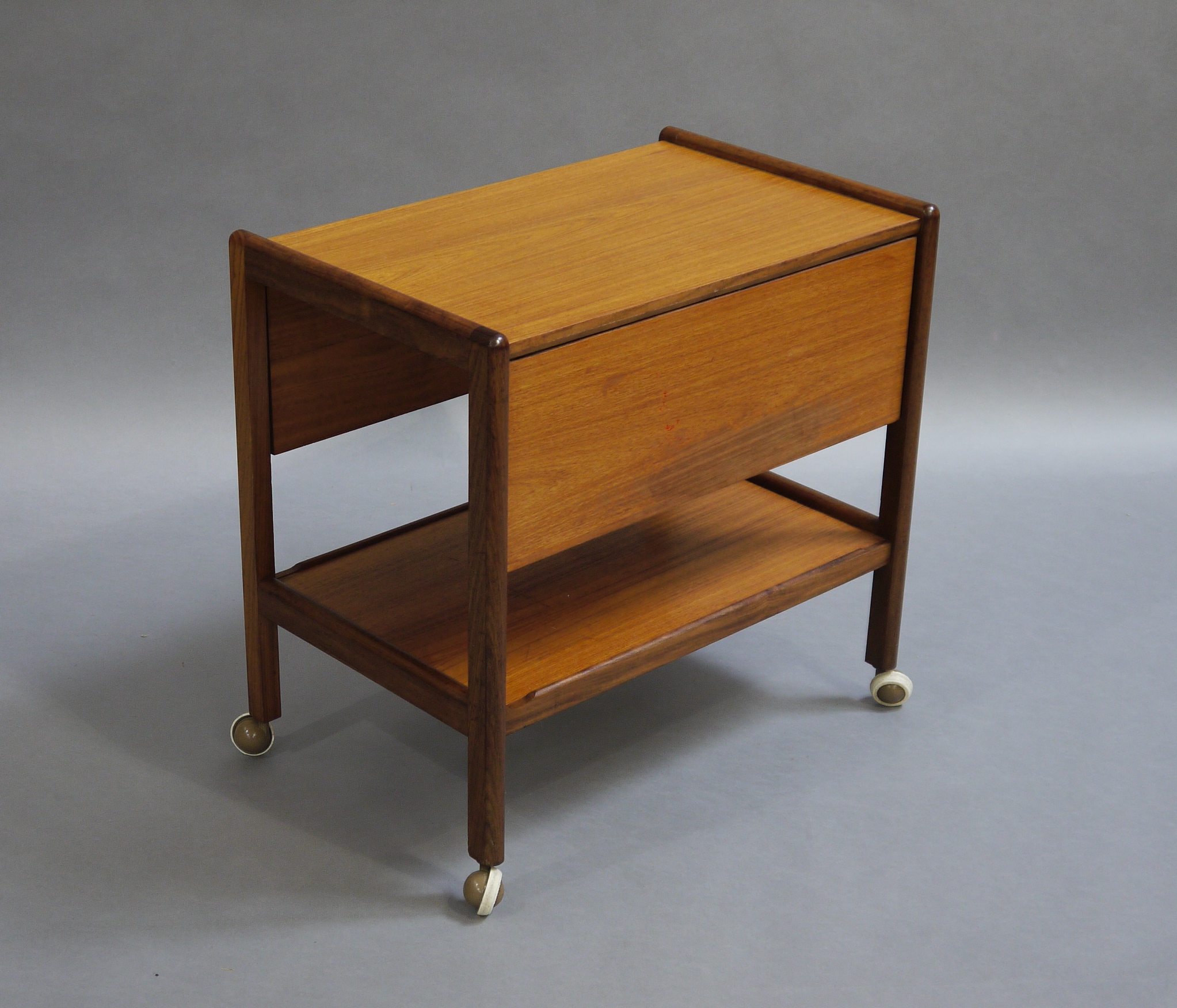 A teak trolley with single drop leaf and under tier on castors