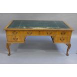 A walnut desk having a gilt tooled leather incised writing surface,