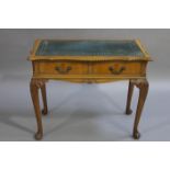 En suite with the preceding lot is a walnut side or writing table with gilt tooled leather incised