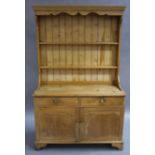 A pine dresser and rack having a moulded cornice above planked back with two shelves,
