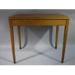 A pale oak and rexine inset writing table on square tapered legs