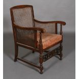 A 1920s polished beech and bergere caned armchair, with turned uprights,