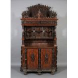 A late 19th century German oak cupboard with ornate cornice above a concave frieze applied leafage,