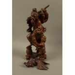 A Chinese hardwood figure of a bearded gentleman and infant holding fish over his shoulder and in