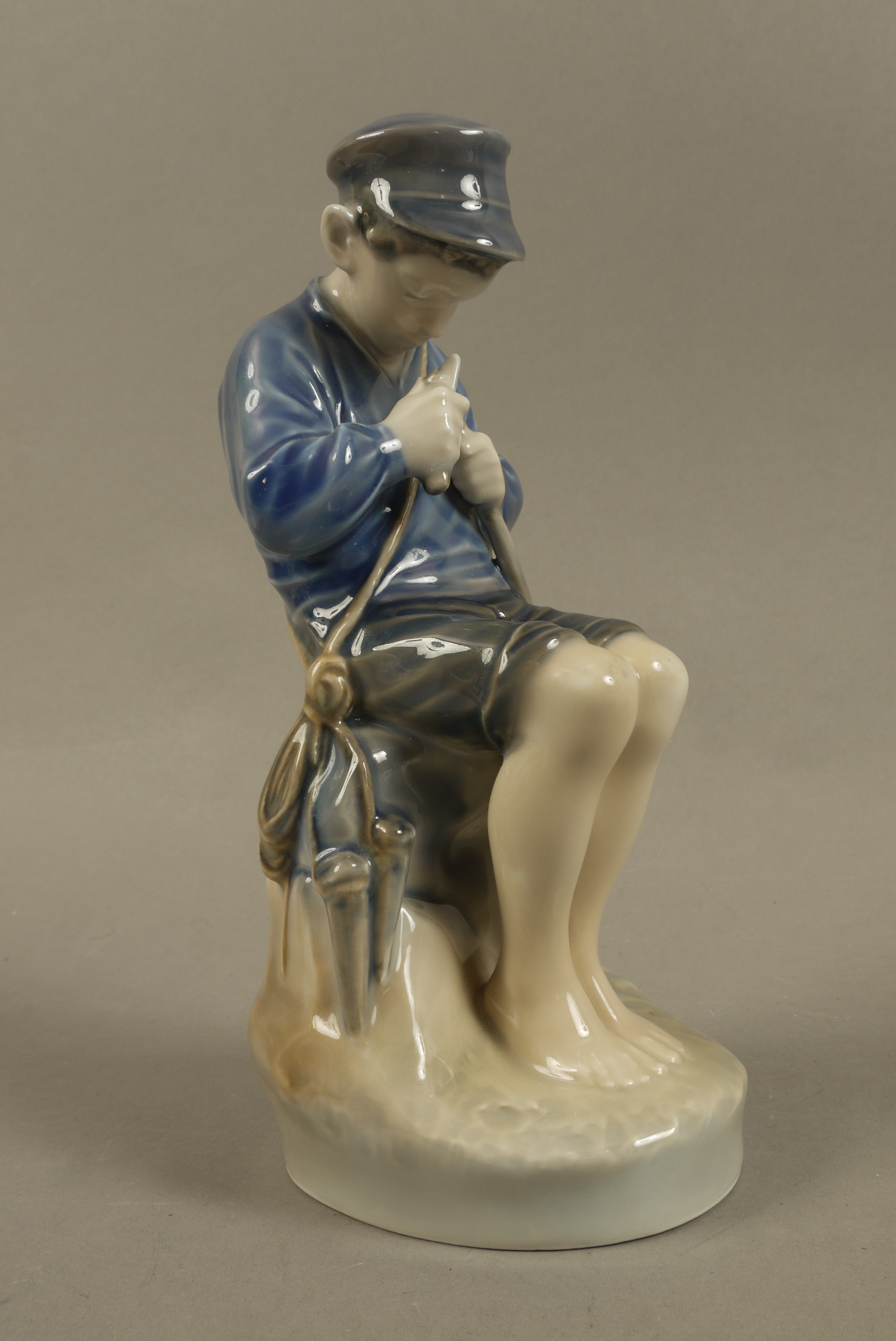 A Royal Copenhagen figure of a young boy seated whittling a stick, no.