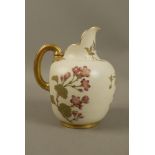 A Royal Worcester ivory ground jug decorated with flowers and leafage, moulded gilt handle,