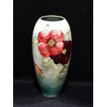 A circular based singed green ground Moorcroft pottery clematis pattern vase, 13"high