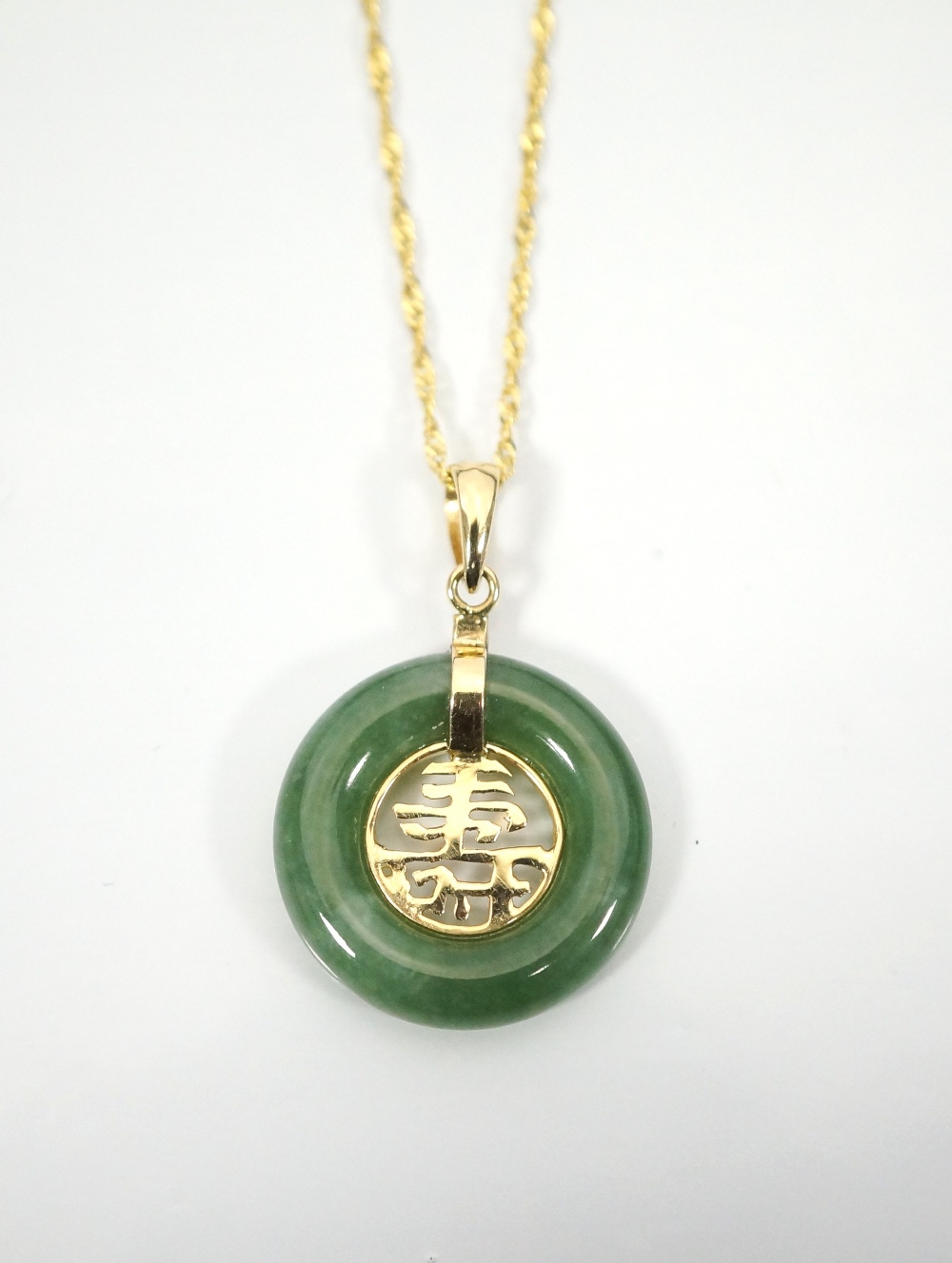 CHINESE CIRCULAR JADE PENDANT with eighteen carat gold Chinese character decoration to the centre,