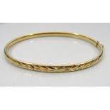 NINE CARAT GOLD BANGLE with engraved decoration and safety clasp, approximately 4.