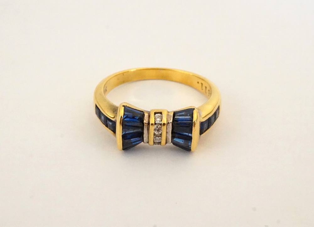 ATTRACTIVE SAPPHIRE AND DIAMOND BOW SHAPED DRESS RING on eighteen carat gold shank,