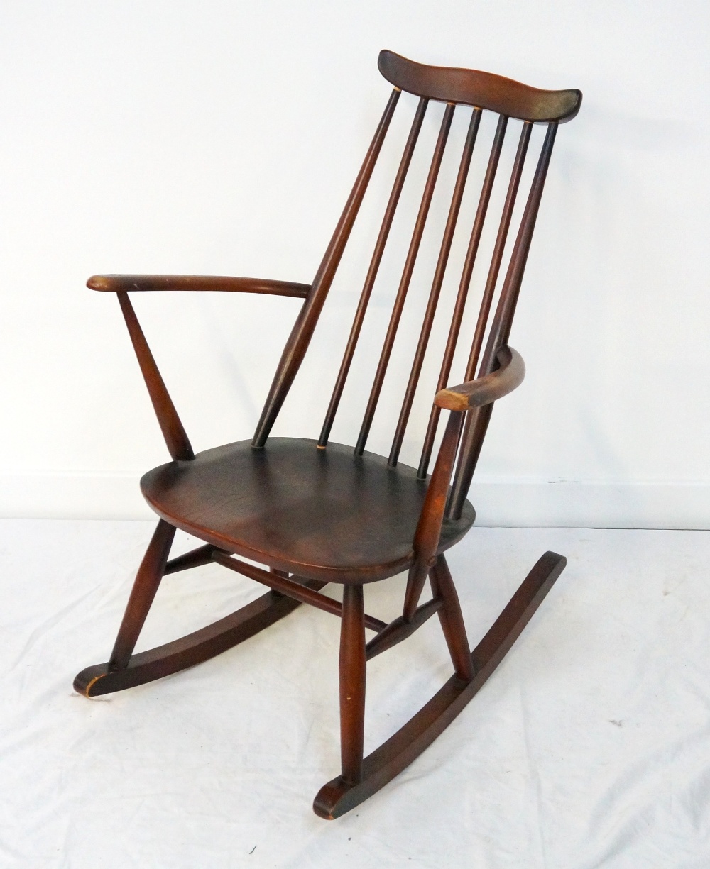 ERCOL ROCKING CHAIR with a shaped top rail above a stick back and shaped arms,