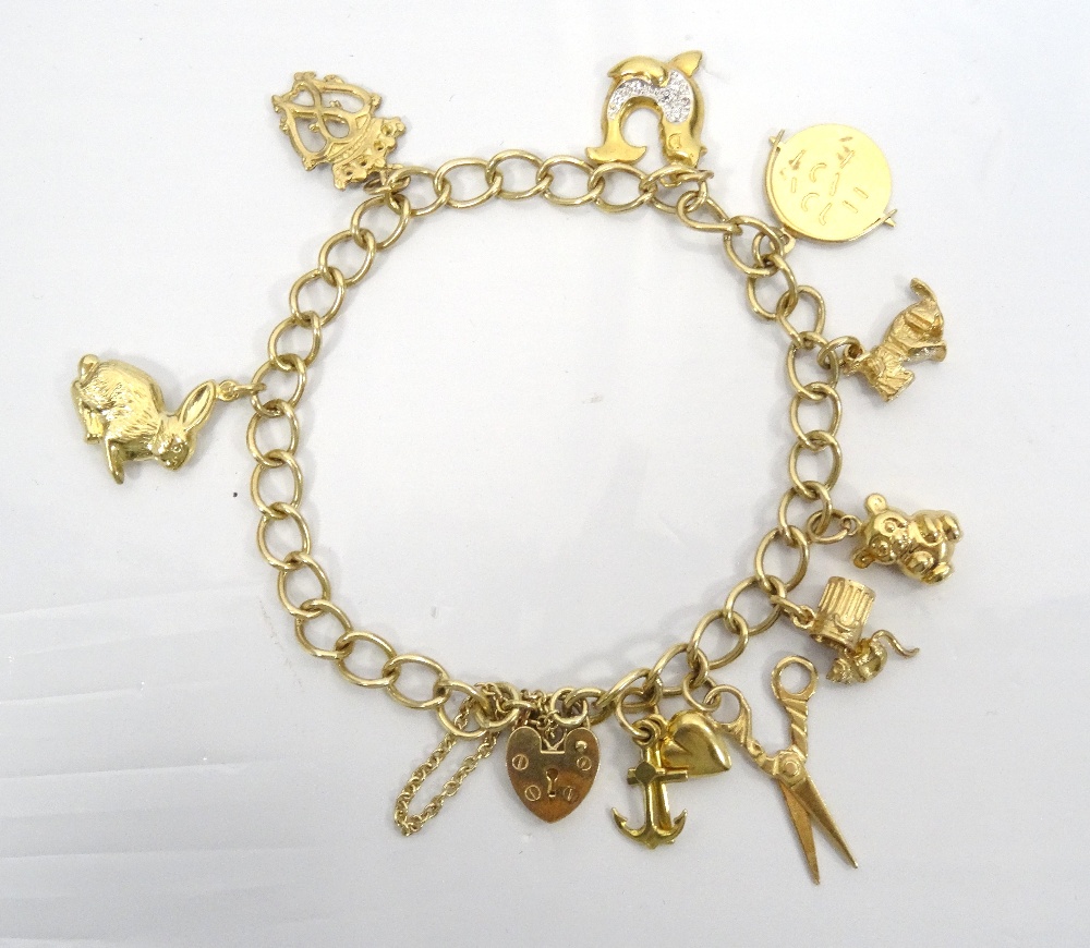 NINE CARAT GOLD CHARM BRACELET with nine carat gold heart clasp, the charms including scissors,