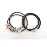 TWO PANDORA DOUBLE BRAIDED BLACK CHARM BRACELETS one with a selection of five charms