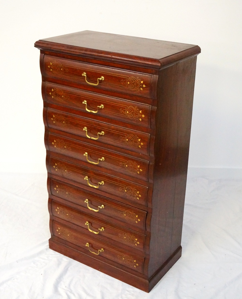 TEAK AND BRASS INLAID CHEST the moulded top above eight shaped drawers with brass handles,