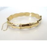 NINE CARAT GOLD BANGLE of shaped design, approximately 12.