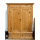 LARGE WAXED PINE WARDROBE with a moulded cornice above two panelled doors and a base of two drawers,