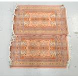 PAIR OF MIDDLE EASTERN STYLE PRAYER MATS each with geometric designs on a pink ground, fringed,