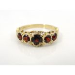 GRADUATED GARNET FIVE STONE RING on nine carat gold shank with moulded and shaped setting,