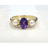 AMETHYST AND PEARL RING the central oval cut amethyst flanked by a pearl to each side,