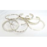 SEVEN SILVER BANGLES of various sizes and designs,