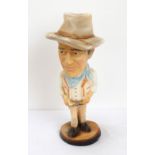 POTTERY FIGURE OF JOHN WAYNE wearing Western attire and raised on circular base,