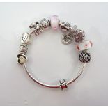 PANDORA SILVER CHARM BANGLE with ten various charms and a clip, the charms including a flower,