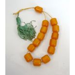 STRING OF FOURTEEN VINTAGE AMBER PRAYER BEADS the barrel shaped beads of butterscotch colour,