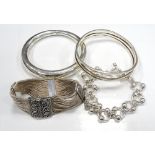 FOUR SILVER BRACELETS AND BANGLES including a multi chain bracelet with decorative relief scroll