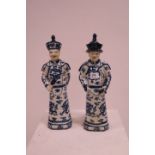 A PAIR OF ORIENTAL GLAZED PORCELAIN BLUE AND WHITE FIGURES in traditional dress with hats 44cm