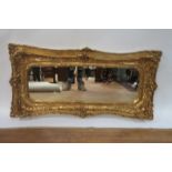 A CONTINENTAL GILTWOOD AND GESSO CUSHIONED MIRROR,