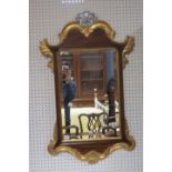 A GEORGIAN STYLE MAHOGANY FRAMED WALL MIRROR the foliate moulded frame with gilded borders headed